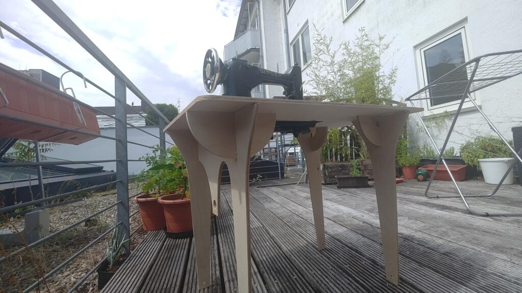 Ein tisch aus holz auf dem eine Nähmaschine steht, der tisch ist gesteckt und nicht verschraubt oder geklebt